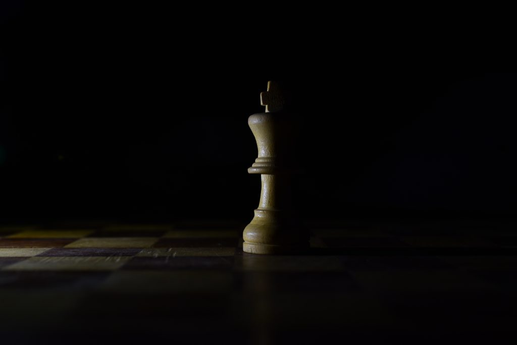 Auf einem Schachbrett steht eine Schachfigur im Schatten