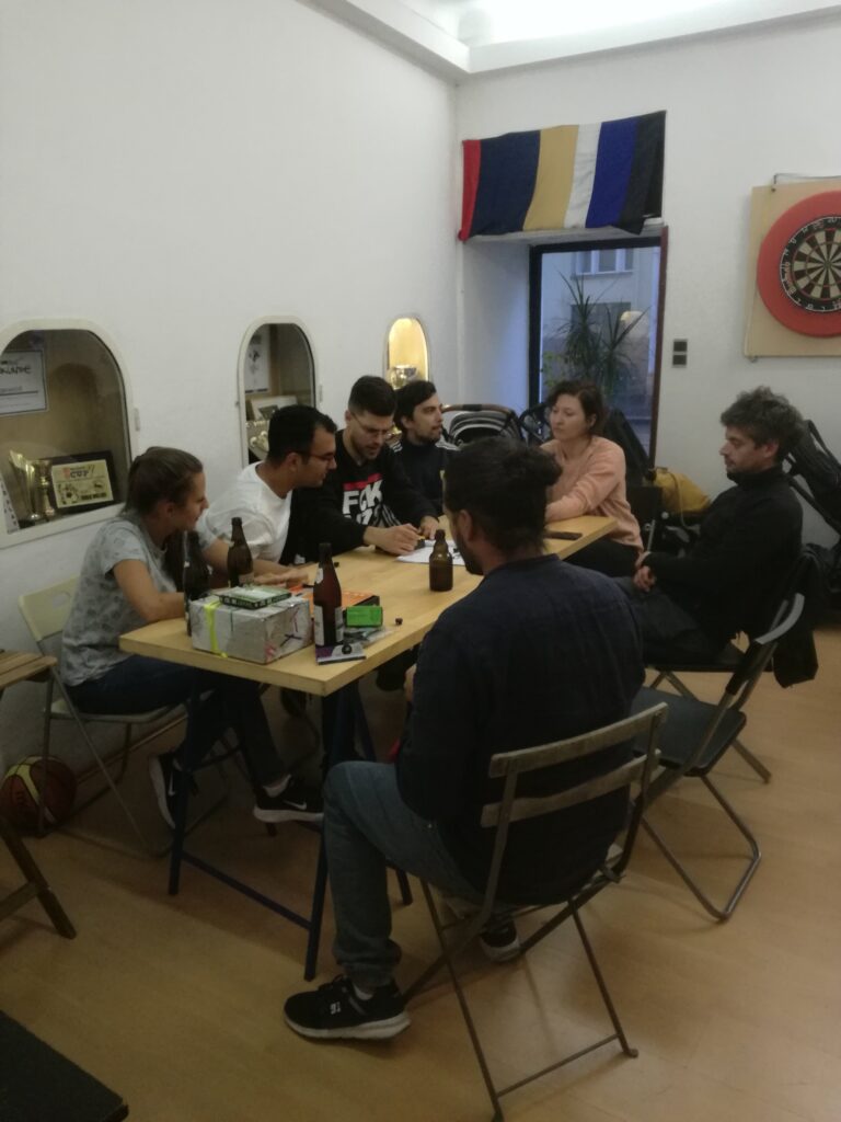 Menschen sitzten um einen Tisch herum und denken angestrengt über die Antwortmöglichkeiten von Smart10 nach.