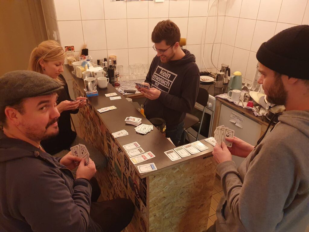Vier Menschen spielen das Monopoly-Kartenspiel an der Theke.